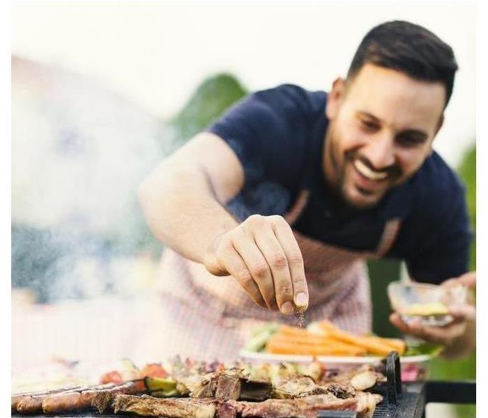 Smiling man seasoning meat on the grill