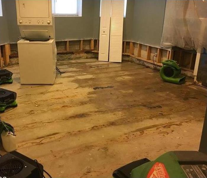 wet wooden floor, air movers placed in a room. Concept of storm damage in a home